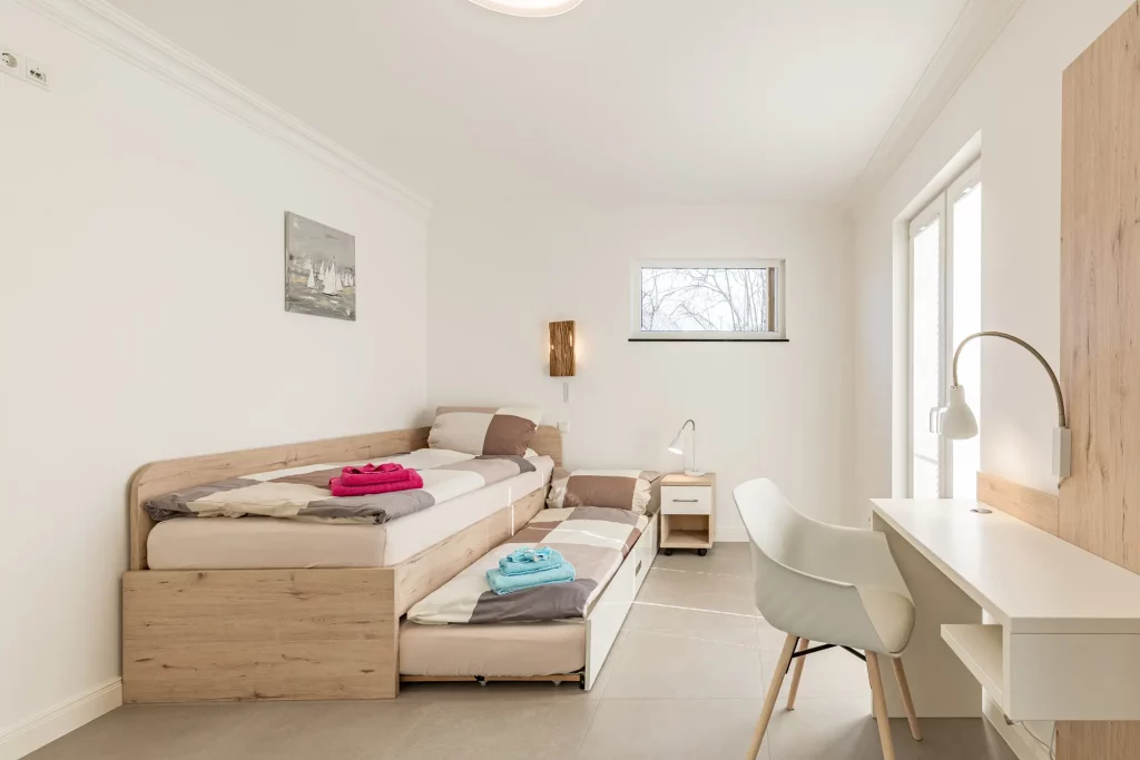 Ferienhaus Saphir Damshagen – Schlafzimmer mit ausziehbarem Bett und kleinem Arbeitsbereich